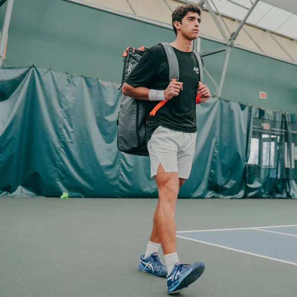 Tennis backpack with a racket holder worn by player walking confidently on an indoor court