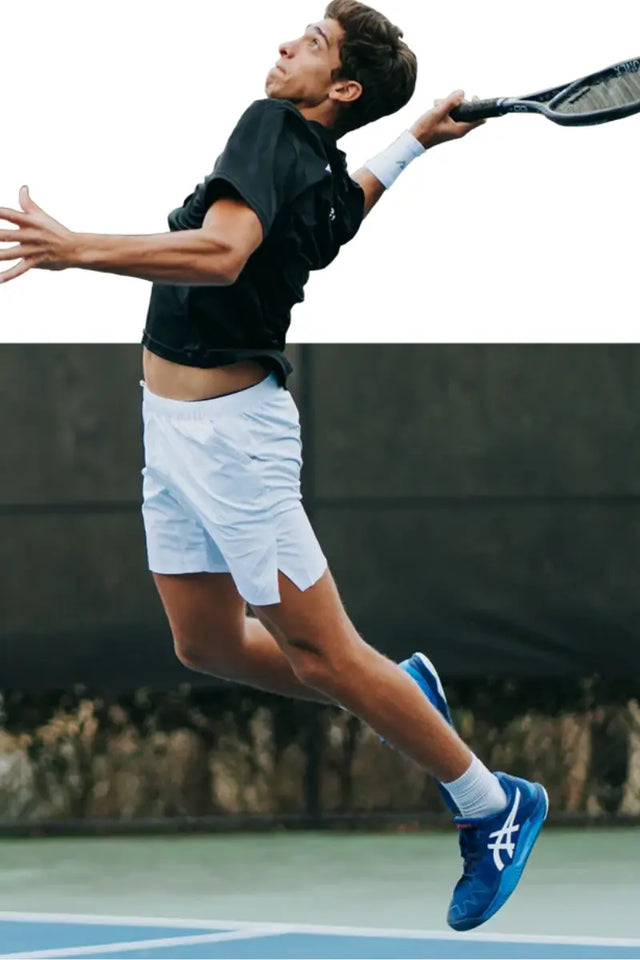 Tennis player jumps mid-air for a powerful shot while gripping a tennis racket firmly