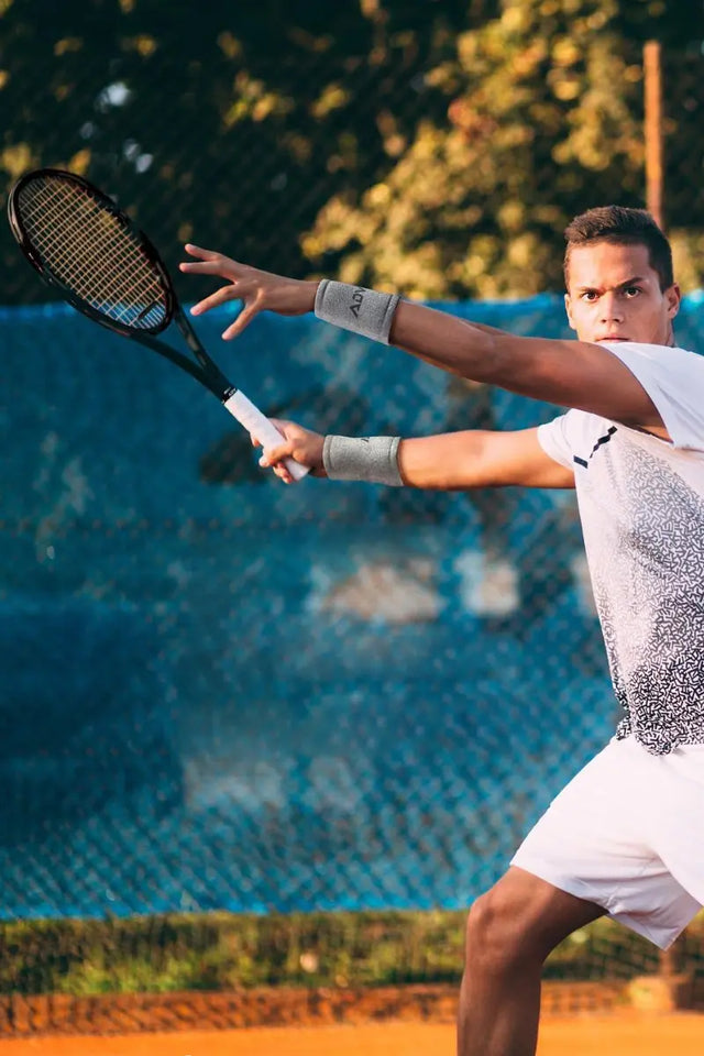 Tennis player wearing custom tennis wristbands while executing a forehand stroke on a clay court.