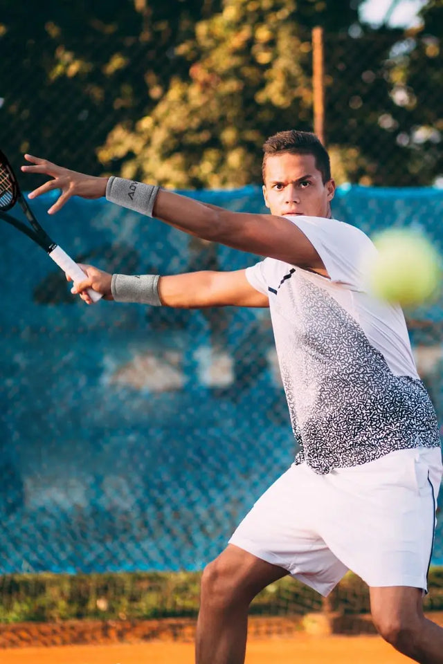 Tennis overgrip for sweat on a male player's racket as he prepares to return a shot on a clay court