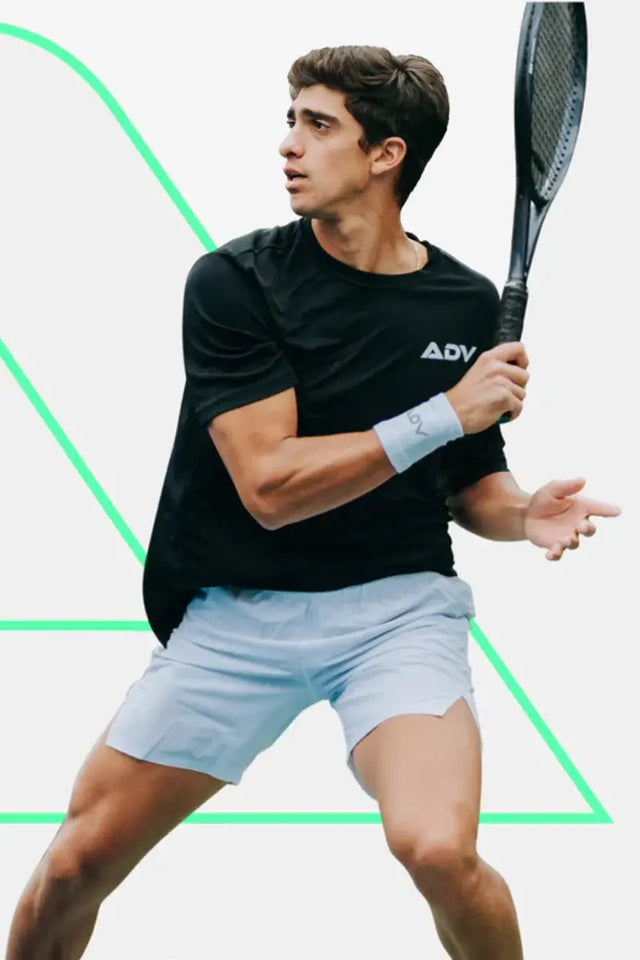 Tennis wristbands featured on a male player in action pose wearing a black shirt and holding a racquet.