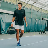 Tennis racket backpack carried by a player on court, featuring a compact yet spacious design with multiple compartments, ideal for storing rackets, gear, and essentials for match day.
